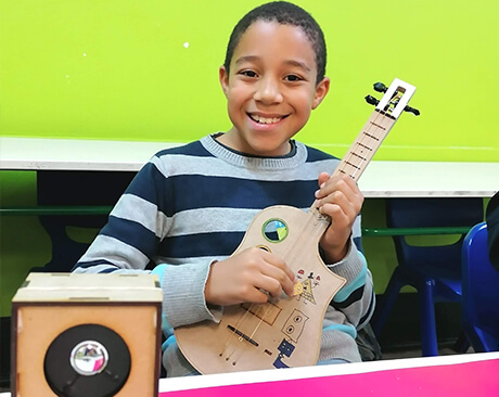 Criança a tocar guitarra montada por ele - TheInventors