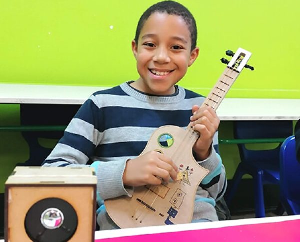 Criança a tocar guitarra montada por ele - TheInventors